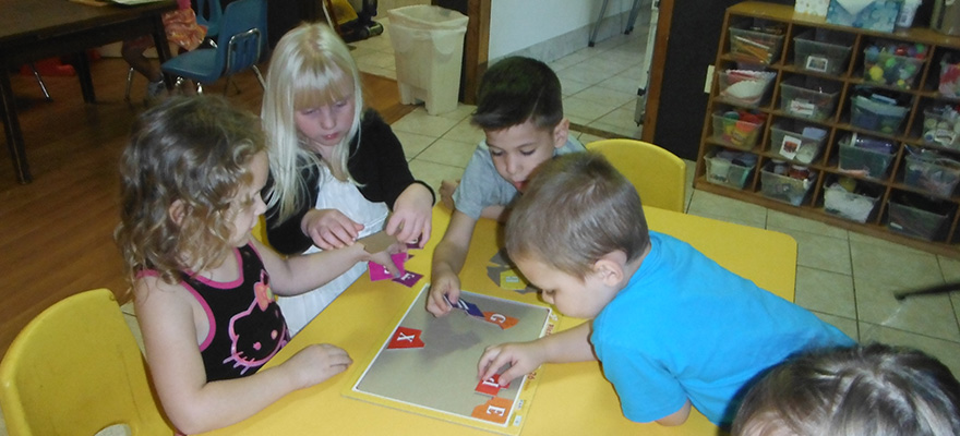 Children working together at a table with classroom learning materials.